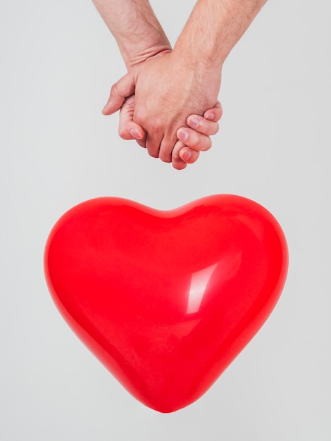 Close-up of gay couple holding hands with balloon