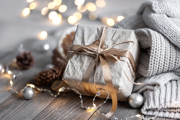 Close-up of a gift box, details of a festive Christmas decor and knitted elements on a blurred background with bokeh.