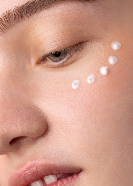 Free photo close up girl applying eye cream