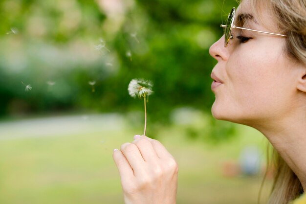 Close-up girl blowing dandelion