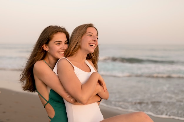Close-up of a girl carrying her friend from behind on beach