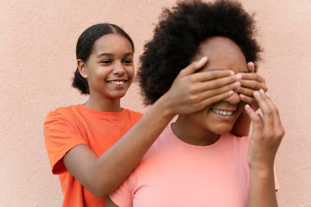 Free photo close up girl covering friend's eyes