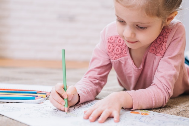 色鉛筆で本を描く少女のクローズアップ