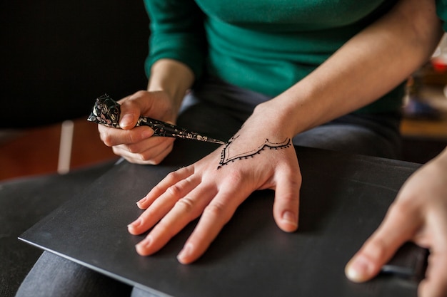 Close-up of a girl drawing heena over female's hand