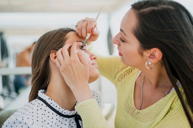 Close-up girl getting makeup from friend