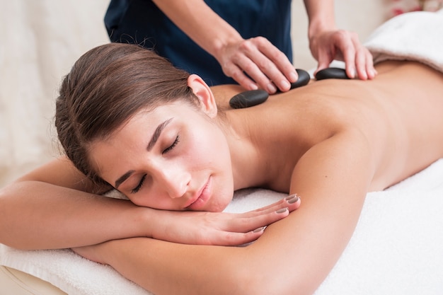 Close-up girl getting stone spa treatment