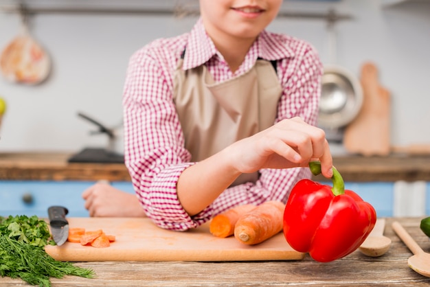 Close-up of a girl holding bell pepper in hand leaning on table