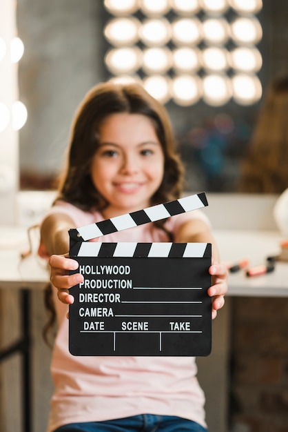 Close-up of girl holding clapper board