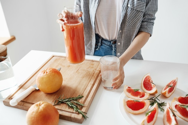 Close up of girl holding glass jar with grapefruit detox smoothie for breakfast. Healthy nutrition concept.