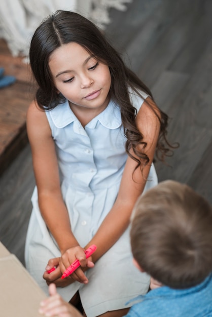 Close-up of a girl holding pink marker looking at boy