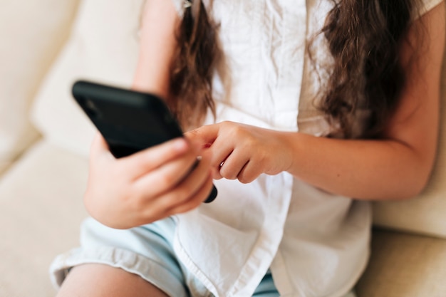 Foto gratuita ragazza del primo piano che tiene uno smartphone