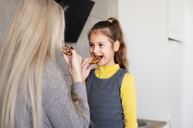 Free photo close up on girl and mom eating cookies