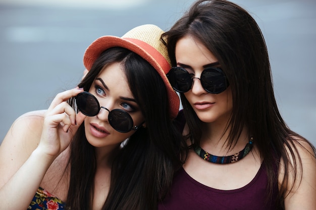 Close-up of girl playing with her sunglasses next to her friend