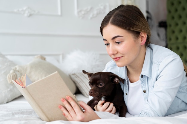 犬と一緒にベッドで読書のクローズアップの女の子