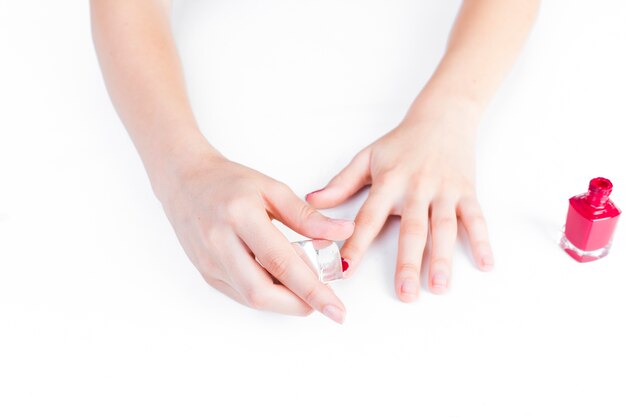 Close-up of a girl's hand applying red nail polish