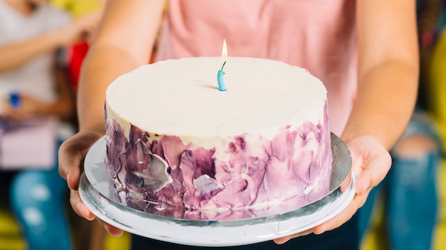 Close-up of a girl's hand holding birthday cake