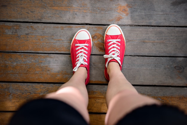 Close up of girl's legs in red keds. From above.