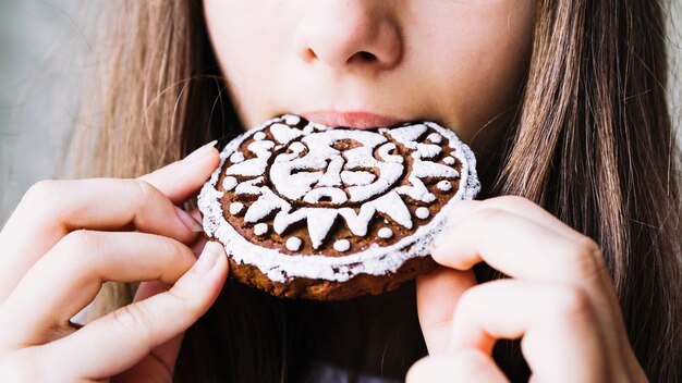 Primo piano della bocca della ragazza che mangia i biscotti di glassa