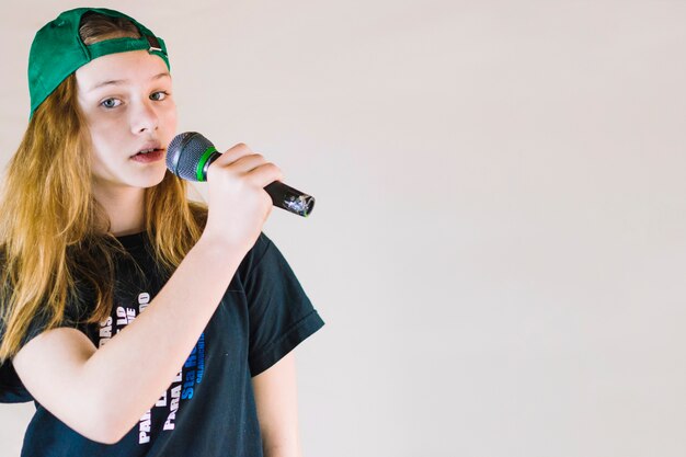 Крупный план девушка петь песню с микрофоном на цветном фоне