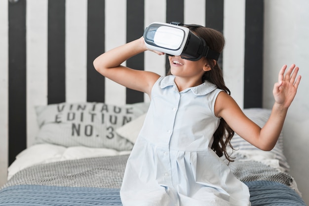 Close-up of a girl sitting on bed wearing virtual reality goggles