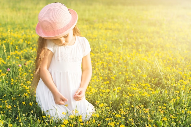 Close-up of a girl sitting in the meadow picking yellow flowers