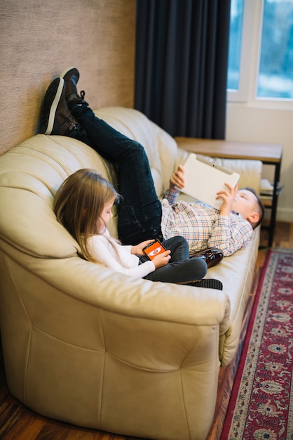Close-up of a girl sitting near the brother looking at digital tablet on sofa