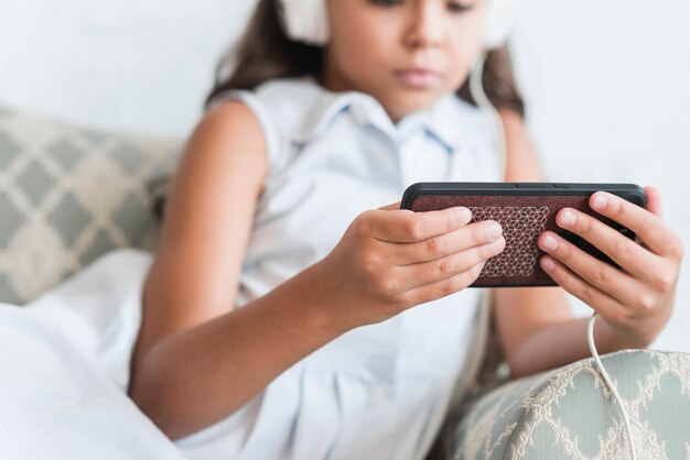 Close-up of a girl sitting on sofa holding cell phone