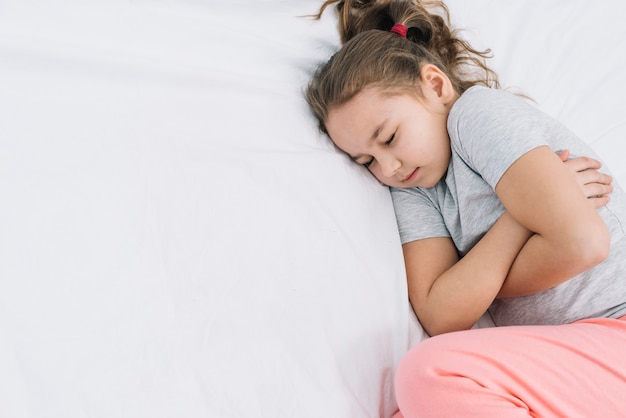 Foto gratuita primo piano di una ragazza che dorme sul letto bianco con dolore