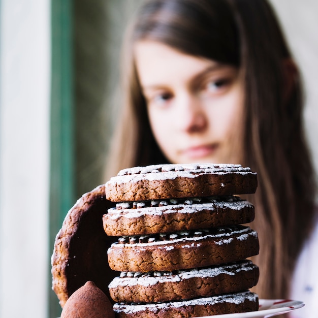 Foto gratuita primo piano della ragazza dietro la pila di biscotti