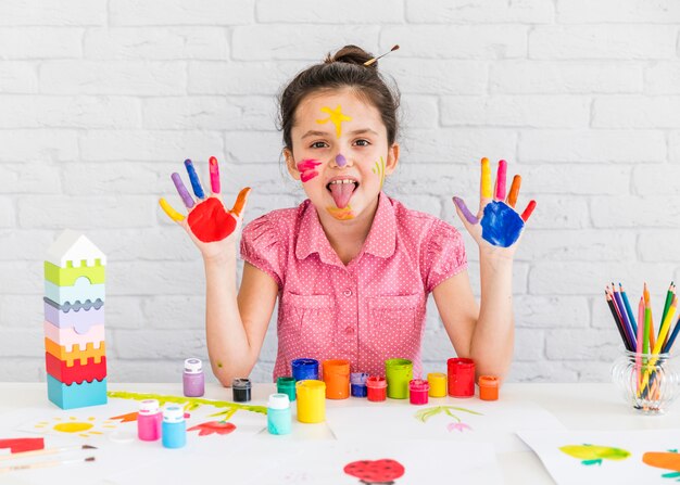 close-up of a girl sticking out her tongue showing her two painted hands