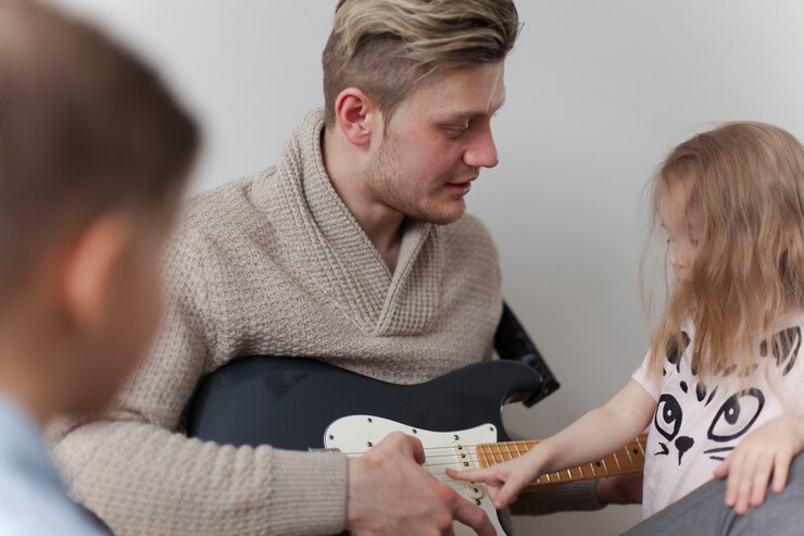 Free Photo close-up of girl touching her father's guitar