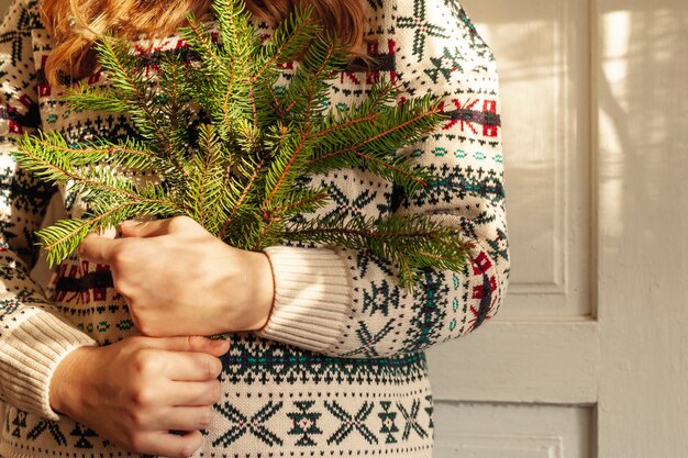 Close-up girl with cute sweater and fir tree twigs