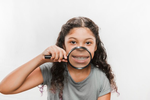 彼女の歯を示す虫眼鏡と女の子のクローズアップ