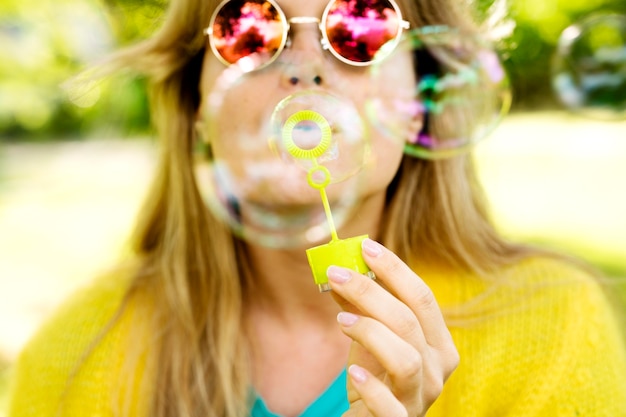 Foto gratuita ragazza del primo piano con gli occhiali da sole che fanno le bolle