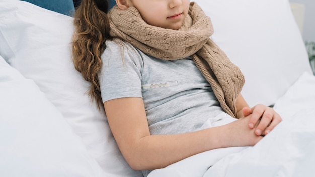 Free photo close-up of girl with woolen scarf around her neck lying on bed