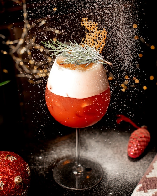 Close up of a glass of citrus cocktail garnished with pine leaves