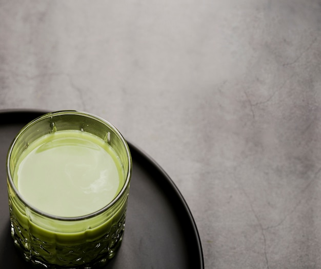 Primo piano di vetro del tè di matcha sul piatto