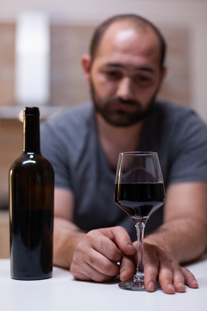 Close up of glass with wine for lonely man in kitchen