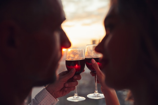 Close up of glasses with wine holding by lovers