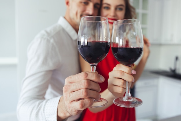 Close up of glasses with wine holding by pretty couple