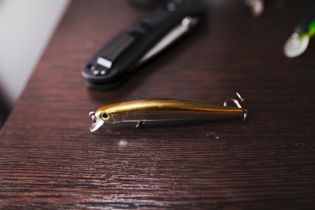 Close-up of a gold colored fishing hook on wooden desk