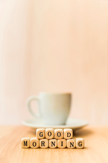 Free photo close-up of good morning cubic blocks with cup of coffee on wooden surface