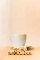 Free photo close-up of good morning cubic blocks with cup of coffee on wooden surface