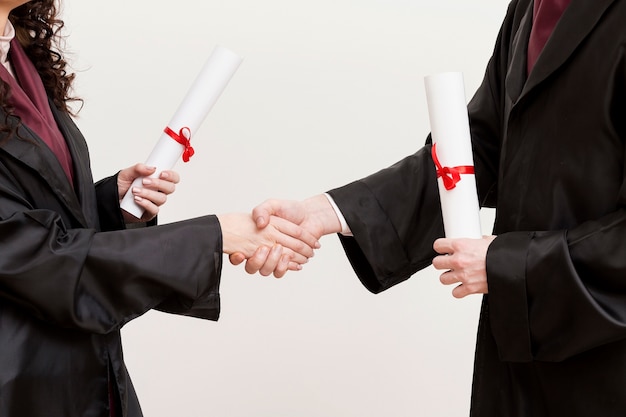 Close-up graduates shaking hands