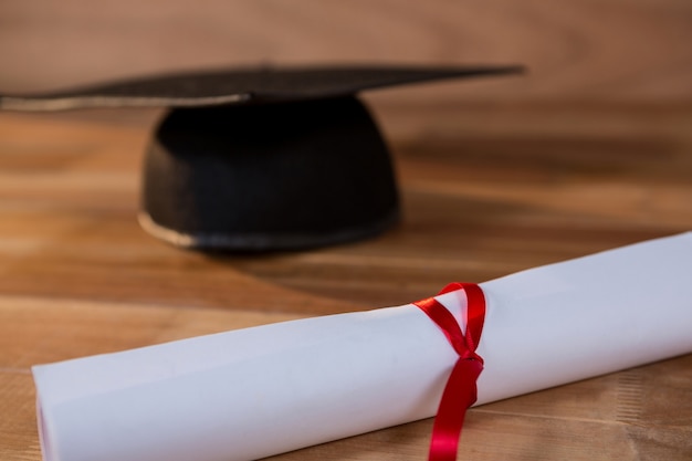 Close-up of graduation certificate with mortar board on a table