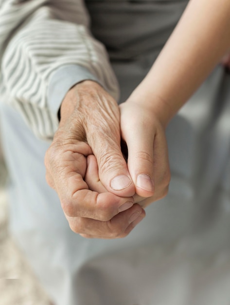 Close-up granddaughter holding grandmothers hand