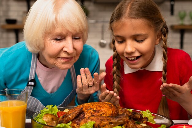 Close-up of grandmother and granddaughter smelling the food