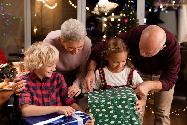 Крупным планом бабушки и дедушки и дети открывают подарки