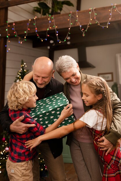 Close up on grandparents and kids opening gifts