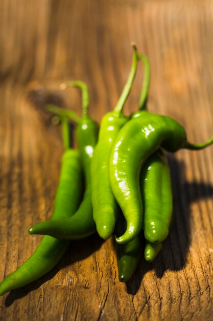 Close-up of green chili peppers on wooden background